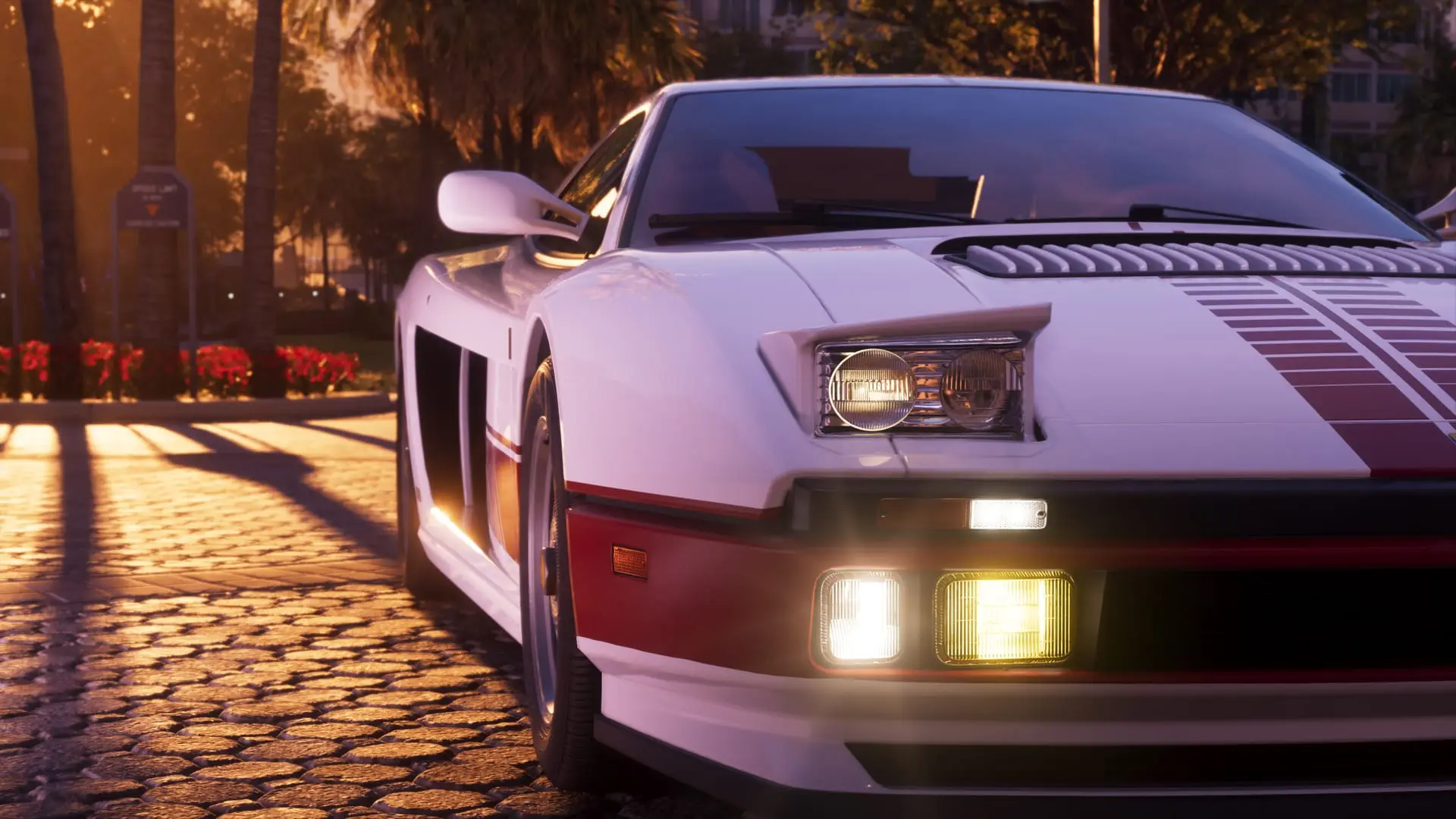 White sports car with red stripes parked on a cobblestone street at sunset, palm trees and sunlight behind.